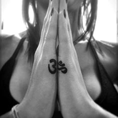 a woman is holding her hands together with the word om on their chest and hand