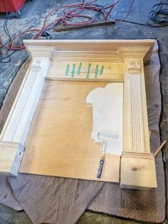 an unfinished piece of furniture being worked on with wood glue and tape to paint the trim