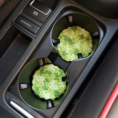 two green cupcakes sitting in the center console of a car