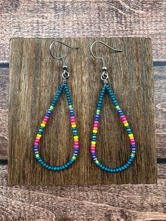 a pair of colorful beaded tear earrings on a wooden board with wood planks