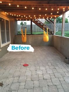 an empty patio with yellow hammocks hanging from the ceiling and lights strung over it