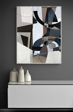 an abstract painting hangs on the wall next to two vases