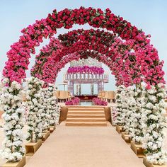 an outdoor wedding setup with pink and white flowers on the arch, steps leading up to the aisle