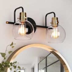 two clear glass globe lights are mounted on the wall above a mirror in a bathroom