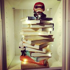 a stack of books sitting on top of a shelf next to a stuffed animal doll