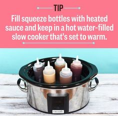 a crock pot filled with condiments sitting on top of a wooden table