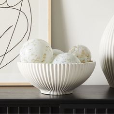 two white vases sitting on top of a table next to an art print and artwork