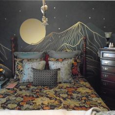 a bed with two pillows on top of it next to a night sky wall mural