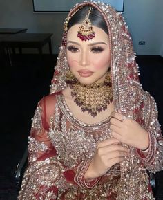 a woman in a red and gold bridal gown with her hands on her chest