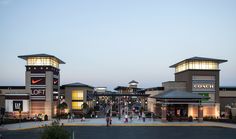 people walking in front of a shopping center at dusk