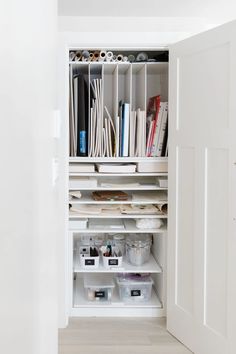 an open closet with white shelves filled with books and other items on the shelf next to it