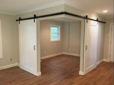 an empty room with sliding doors and hard wood flooring