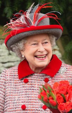 queen elizabeth smiles as she holds flowers