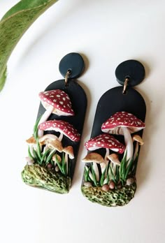 the earrings are decorated with mushrooms and grass