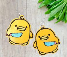 two yellow bird shaped earrings sitting on top of a wooden table