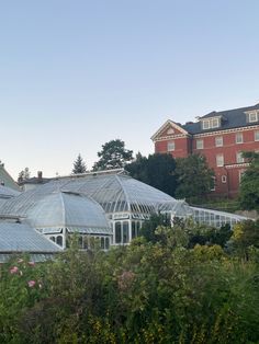 a large building with many windows in the middle of trees and flowers around it,