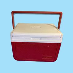 a red and white cooler sitting on top of a blue background with the lid open