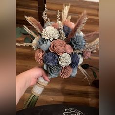 a bridal bouquet made with paper flowers and feathers is being held by a woman