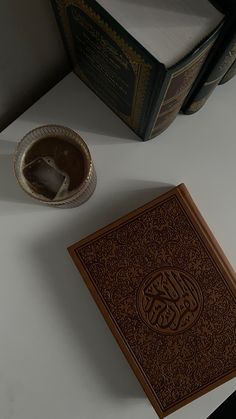 an open book sitting on top of a white table next to a cup and saucer