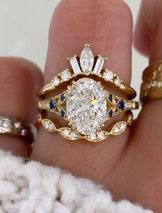 a woman's hand holding two wedding rings with diamond and blue sapphire stones on them