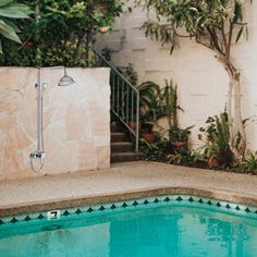 an empty swimming pool in front of a house with stairs leading up to the back door