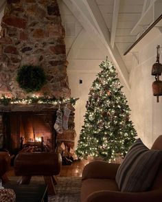 a living room decorated for christmas with a fireplace and large tree in the corner next to it