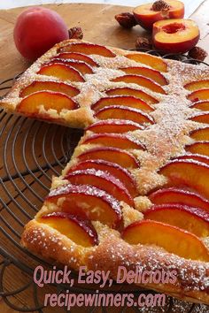 sliced peaches and powdered sugar on top of a cake cooling on a wire rack