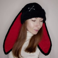 a woman wearing a black and red knitted hat with cross on the side,