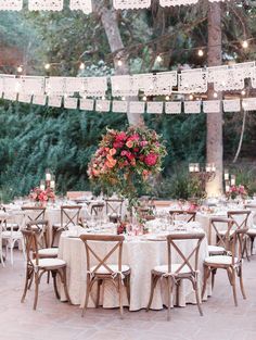 an outdoor dining area with tables, chairs and hanging lights in the middle of it