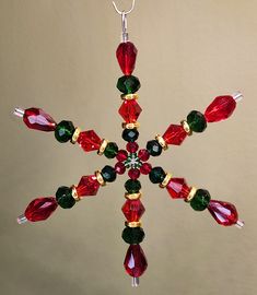 a snowflake ornament with red, green and gold beads on it