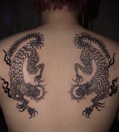 the back of a woman's body with tattoos on her upper and lower back