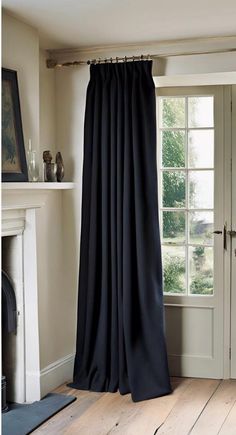 a black curtain hanging from the side of a window next to a fireplace in a living room