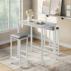 a white table with two stools next to it in front of a large window