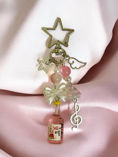 a bottle that is sitting on top of a pink satin material with a star charm attached to it