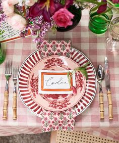 a place setting with pink flowers and greenery