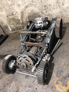 an old engine sitting on the ground next to a cement wall and some metal parts