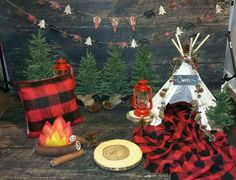 a table topped with red and black plaid pillows next to a teepee tent filled with pine trees