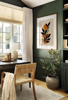 a home office with green walls and white curtains on the windowsill, along with a wooden chair