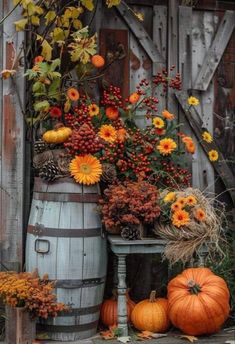 pumpkins and gourds are arranged in front of an old wooden barrel with fall foliage