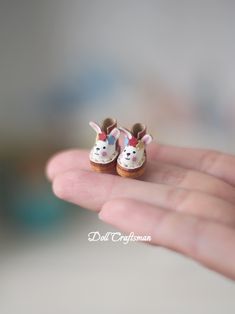 a tiny doll is sitting in the palm of someone's hand, wearing shoes with bunny ears on them