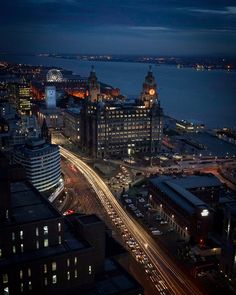 an aerial view of a city at night with cars driving on the road and buildings in the background