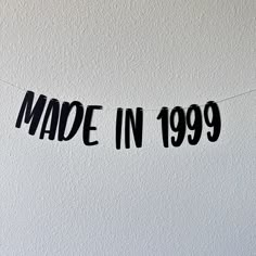 a black made in 1989 sign hanging from a string on a white wall with the words made in 1989 written across it