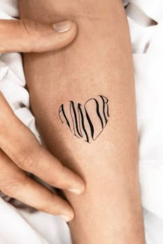 a woman's arm with a heart tattoo on it