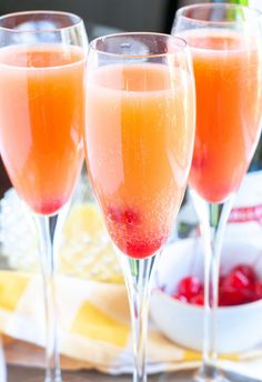 three wine glasses filled with orange juice and cranberry sauce on a tablecloth