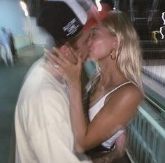 a man and woman kissing each other in front of a store window with people looking on