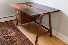 a wooden desk sitting on top of a hard wood floor next to a white wall