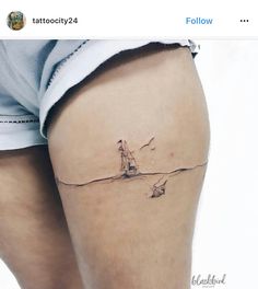 a woman's thigh with a small sailboat tattoo on her left side leg