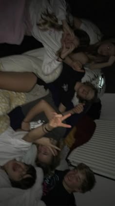 a group of people laying on top of each other in a bed with their hands up