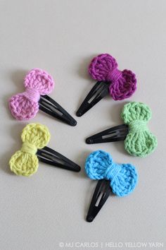 six crocheted hair clips in different colors on a white surface with black handles