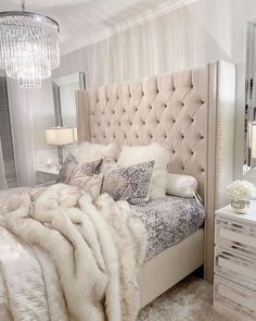 a bedroom with a bed, dresser and chandelier in the middle of it